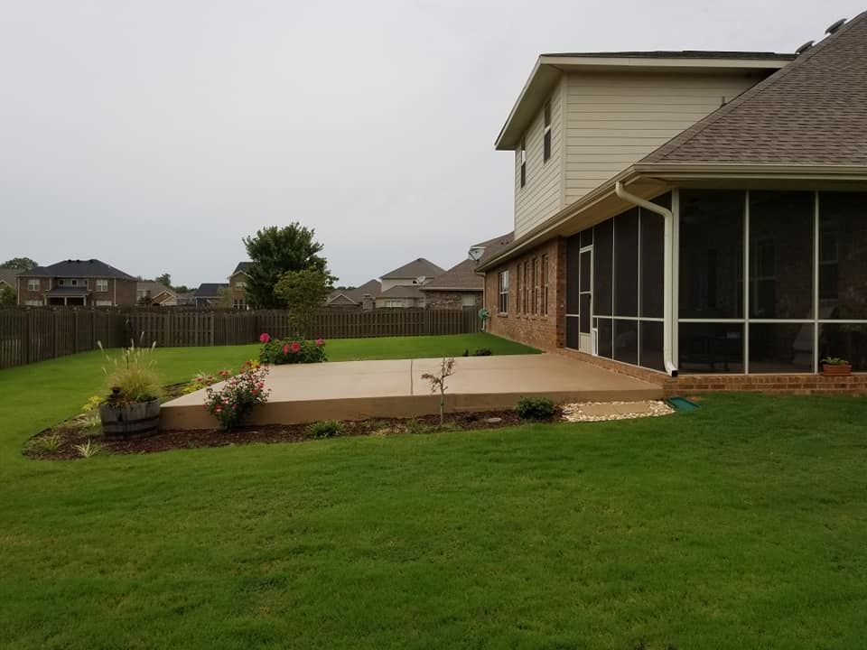 Backyard with a concrete patio, screened porch, and green lawn.