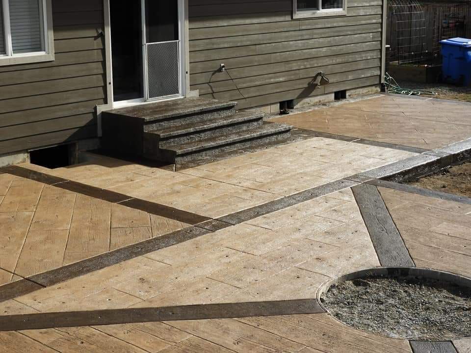 Stamped concrete patio with steps leading to a door and a built-in fire pit.