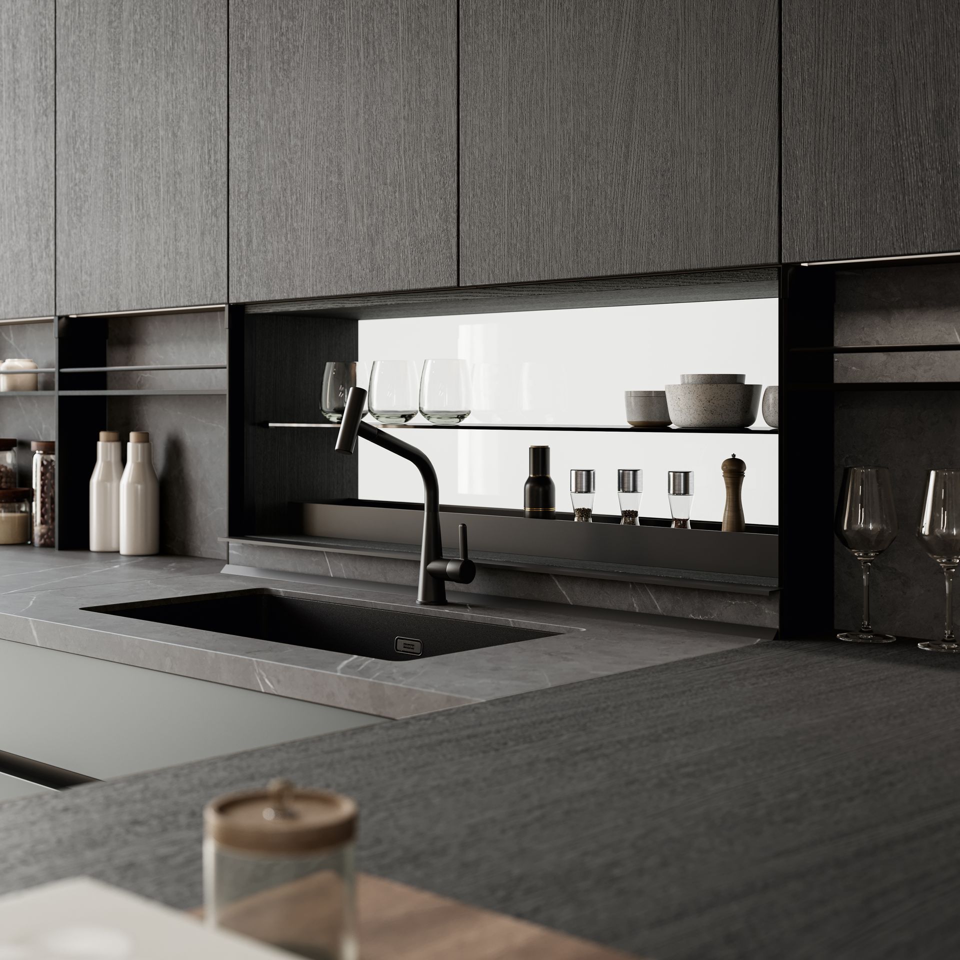 Cucina moderna con mobili scuri, lavello e ripiani a vista su cui sono esposti bicchieri e utensili.