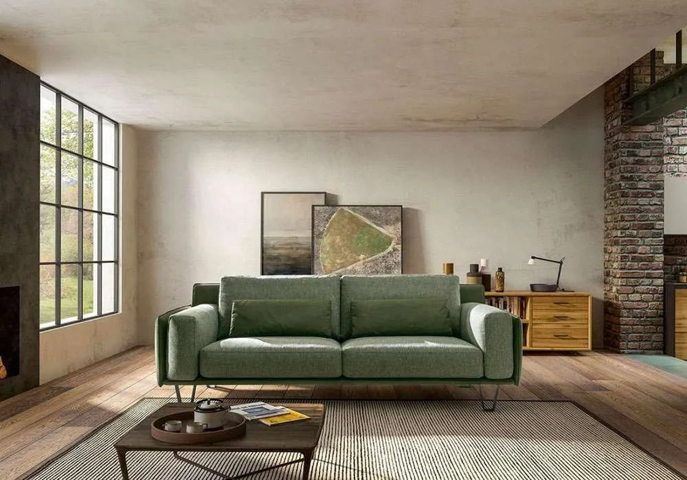 Divano verde in un soggiorno dai toni neutri con tavolino da caffè, opere d'arte e mobili in legno.