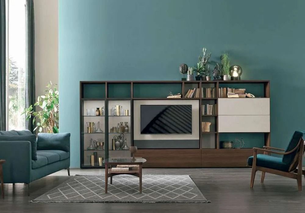 Soggiorno con pareti color verde acqua, mobile porta TV in legno scuro, divano e poltrona.