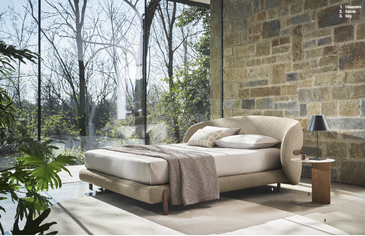 Camera da letto con letto grande, parete in pietra e finestra con vista sugli alberi.