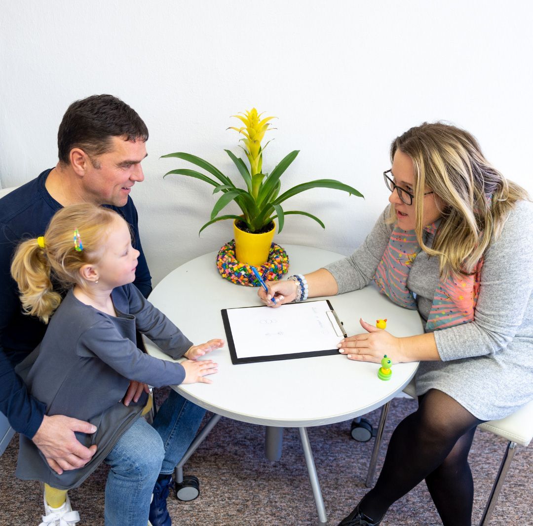 A family, child and father, consults with a professional at a table.