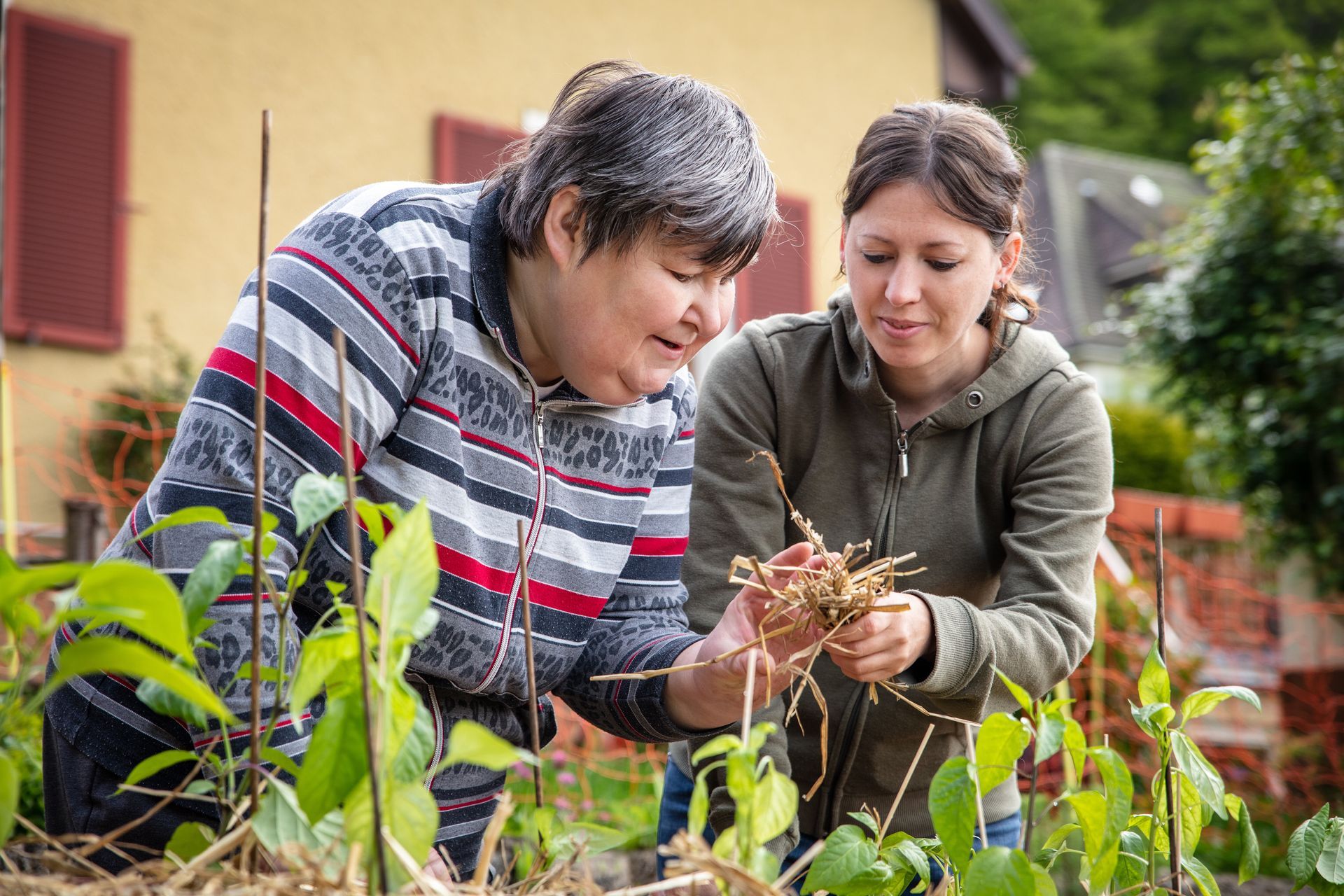 A carer explains continence care to a woman with an intellectual disability in a garden setting.