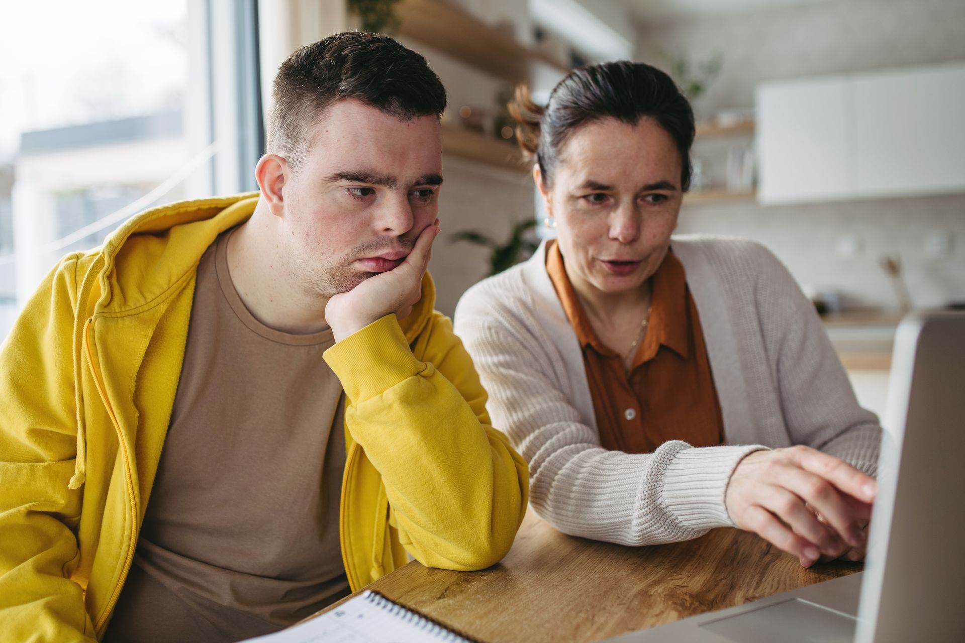 A mother and her son are using the laptop for a telehealth NDIS continence assessment.