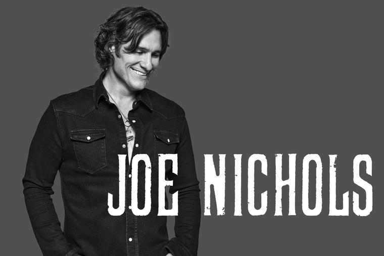 Darryl Worley seated, holding guitar, in front of a logo with his name on a black background.