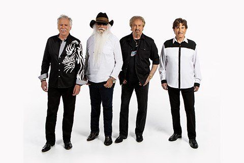 Four men in casual attire stand together.