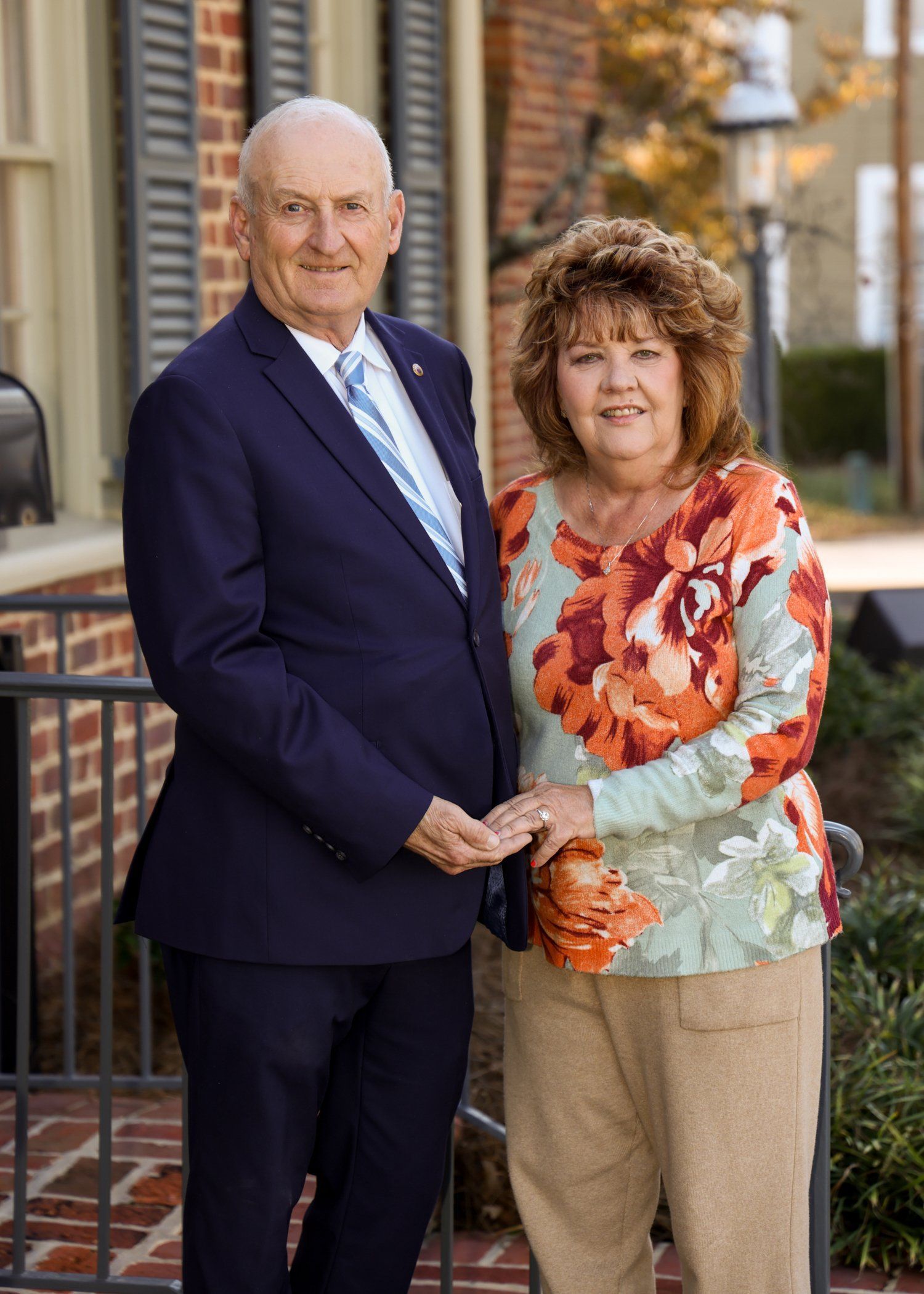 A man and a woman are holding hands in front of a brick building.