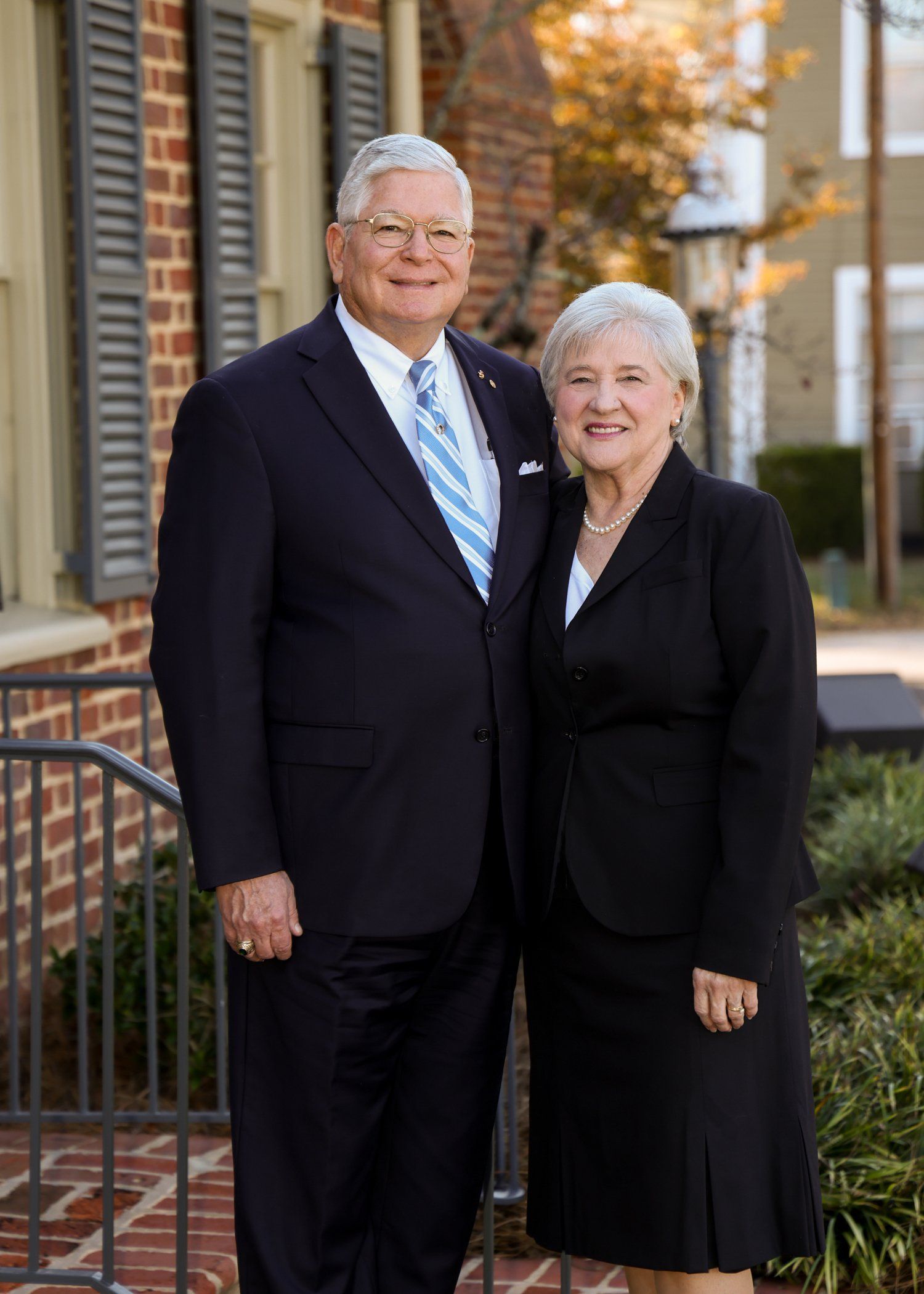 A man and a woman are posing for a picture in front of a brick building.