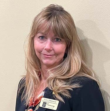 A woman with long blonde hair is wearing a name tag and a black jacket.