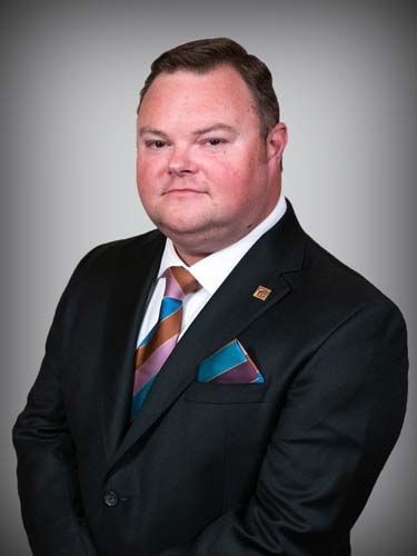 A man in a suit and tie is standing with his arms crossed.