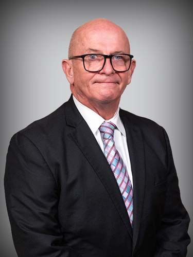 The man is wearing a suit and tie and glasses.