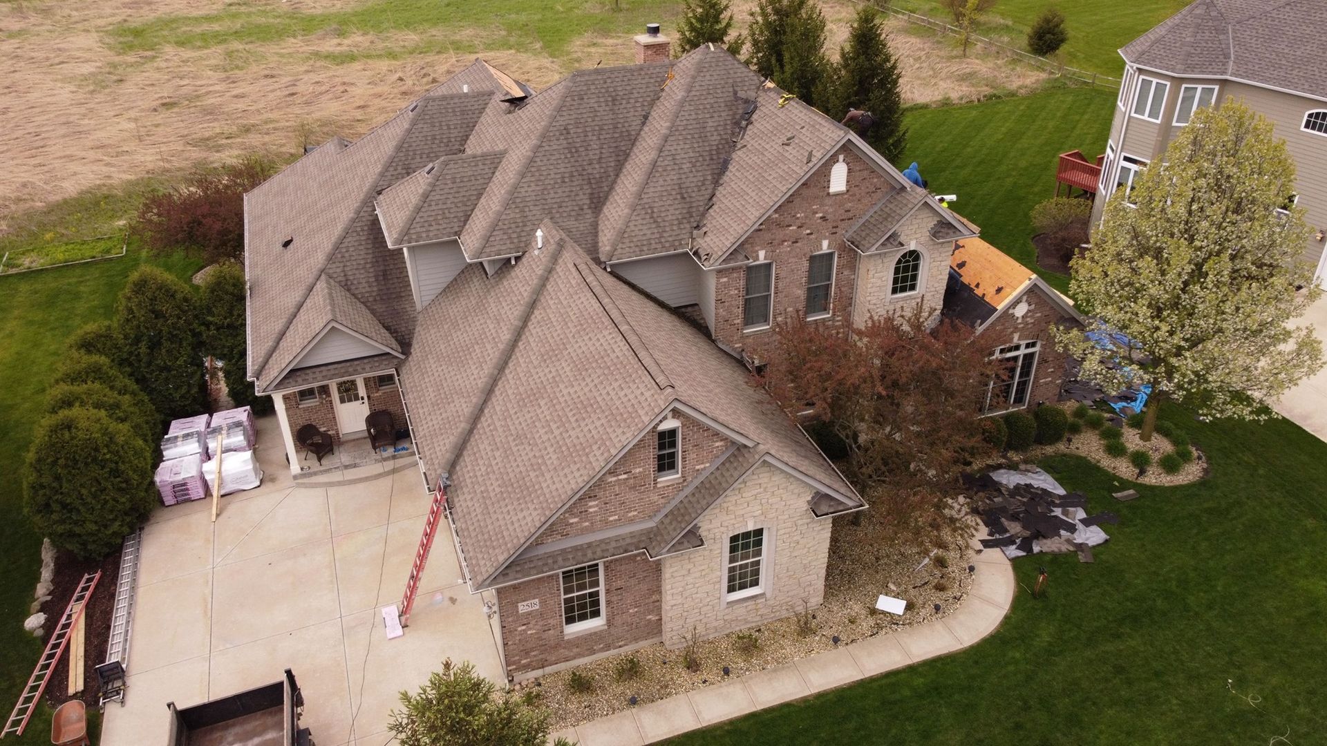 An aerial view of a large house with a roof being installed.