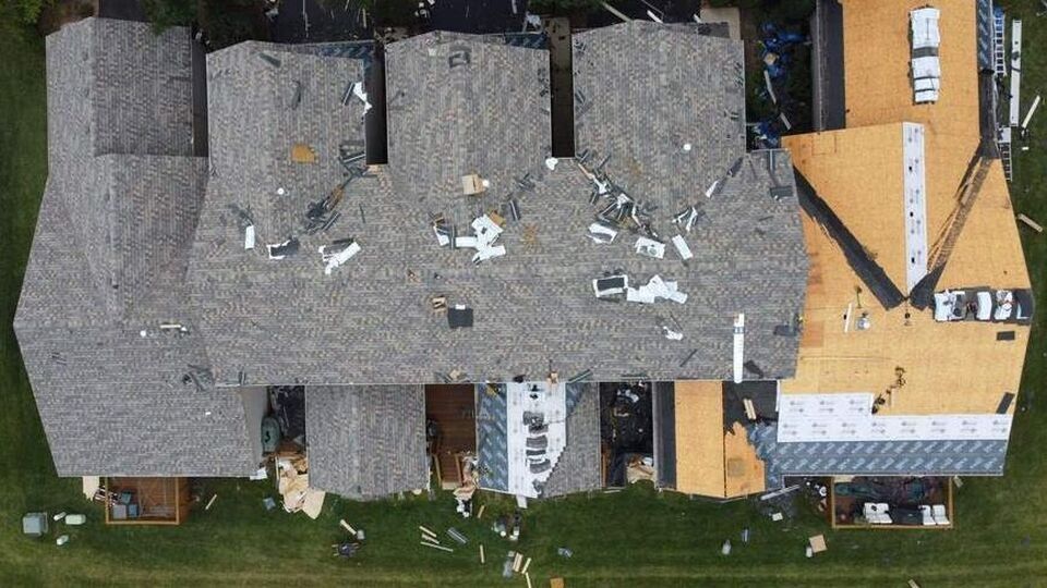 An aerial view of a house with a roof that has been damaged by a storm.
