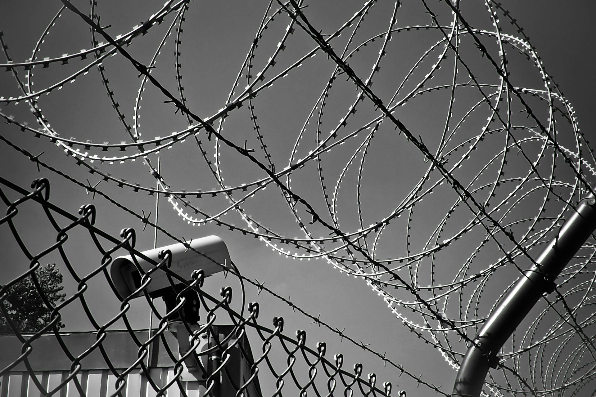 barbed wire and razor wire with security camera, black and white photo.
