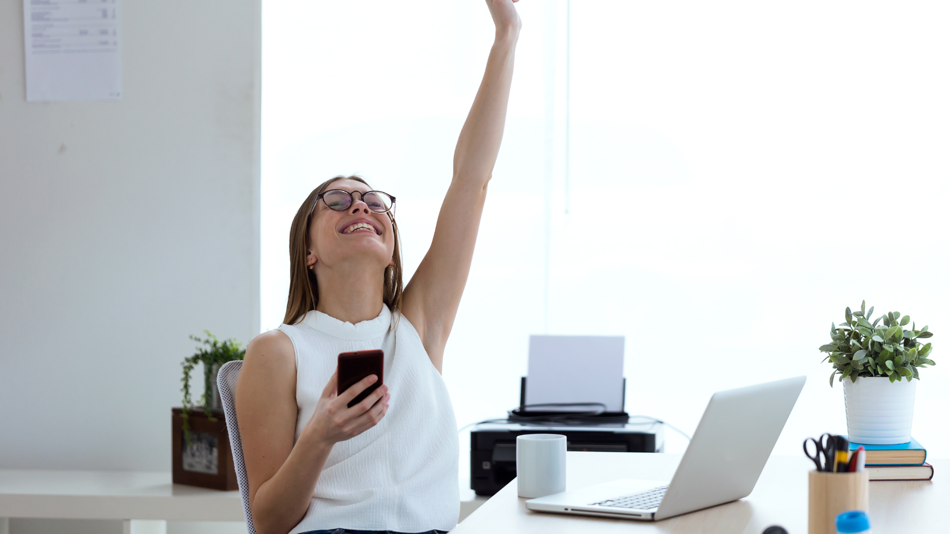 Woman sitting at desk with her arm in the air