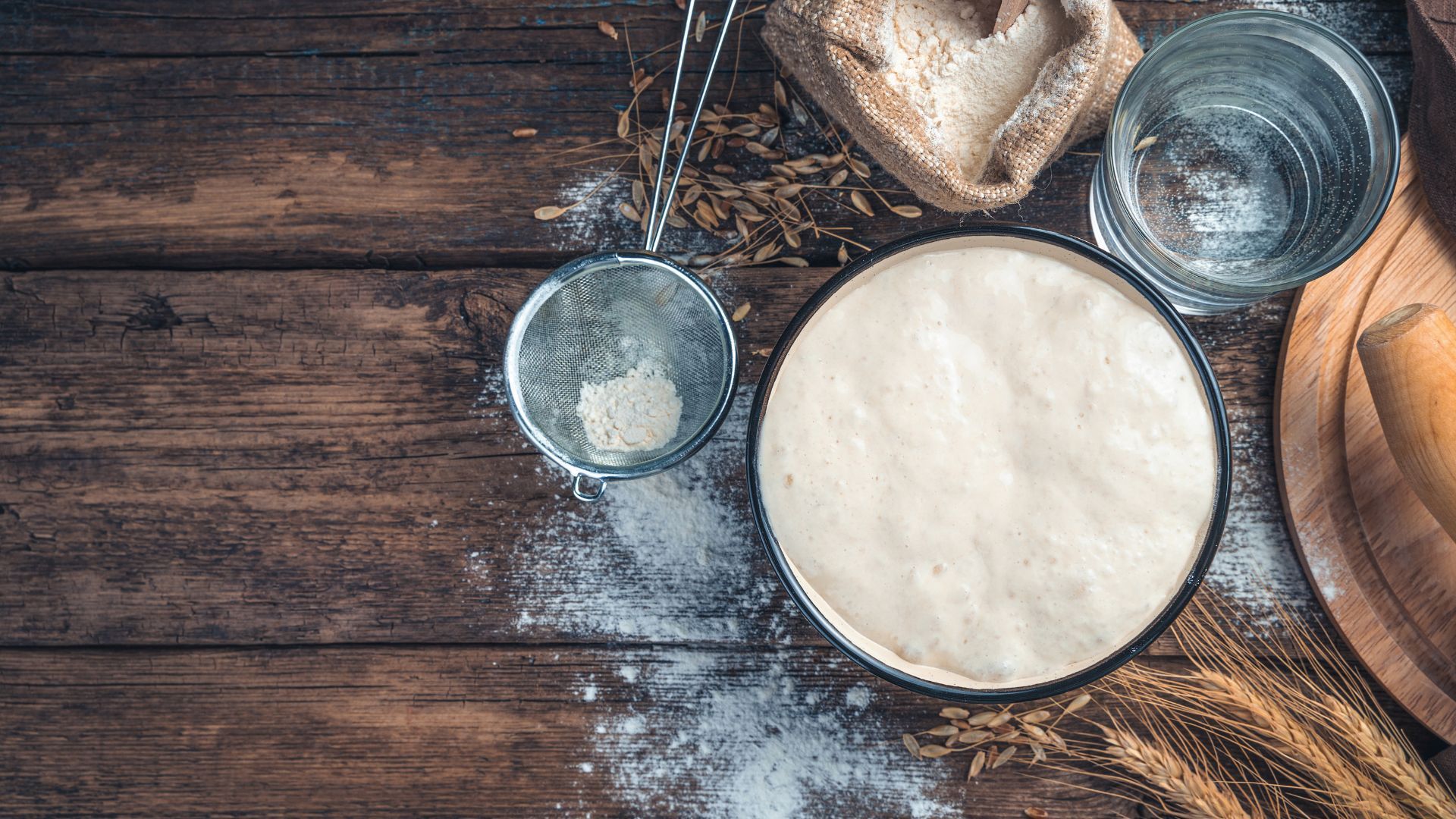 Kitchen table with flour, water, sieve to make sourdough bread