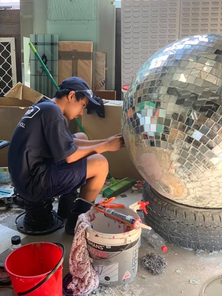 Person Attaching Tiles to a Large Mirror Ball — Innisfail Glass & Aluminium in Innisfail, QLD