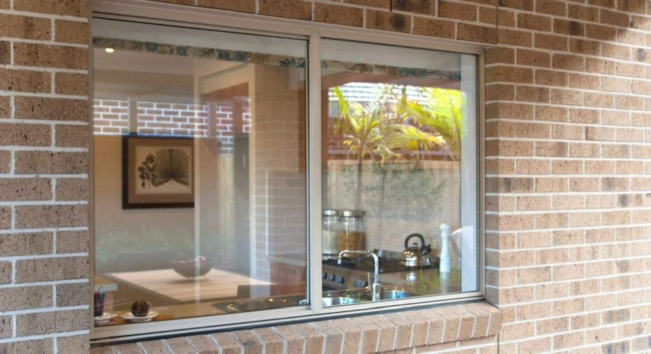 Window in a Brick Wall Reflecting an Interior — Innisfail Glass & Aluminium in Innisfail, QLD