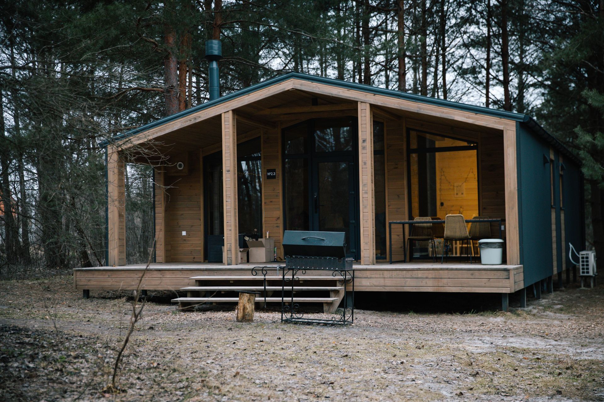 A small wooden house with a porch in the middle of a forest.