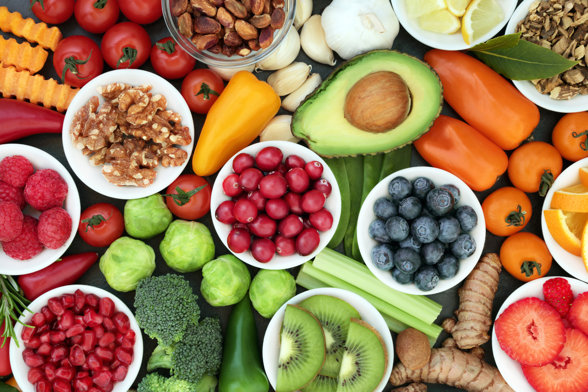 A variety of fruits and vegetables in bowls on a table.