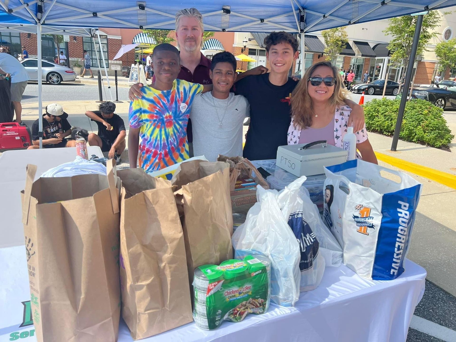 A group of people standing around a table with bags of food.