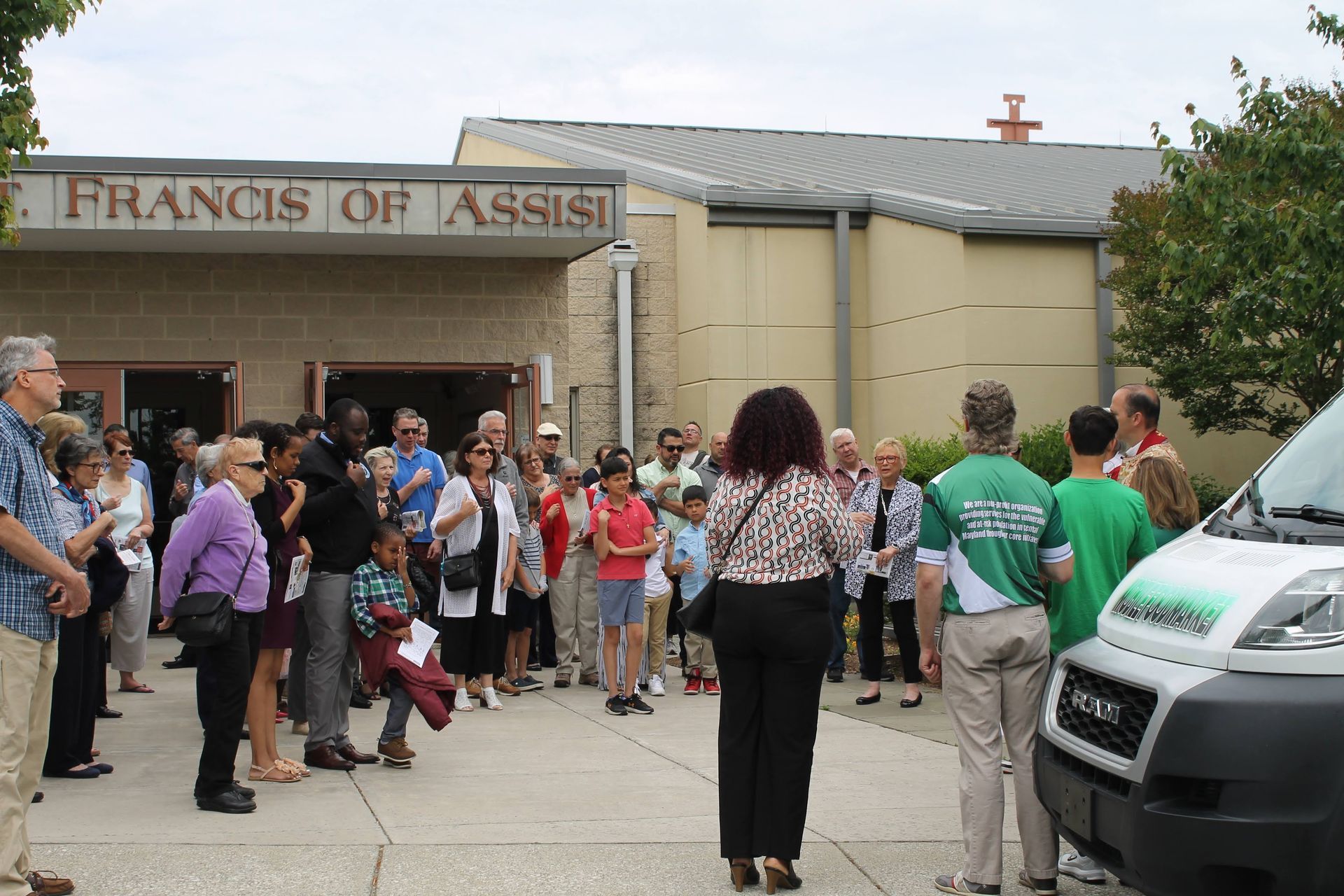 A group of people standing in front of a building that says francis of assisi