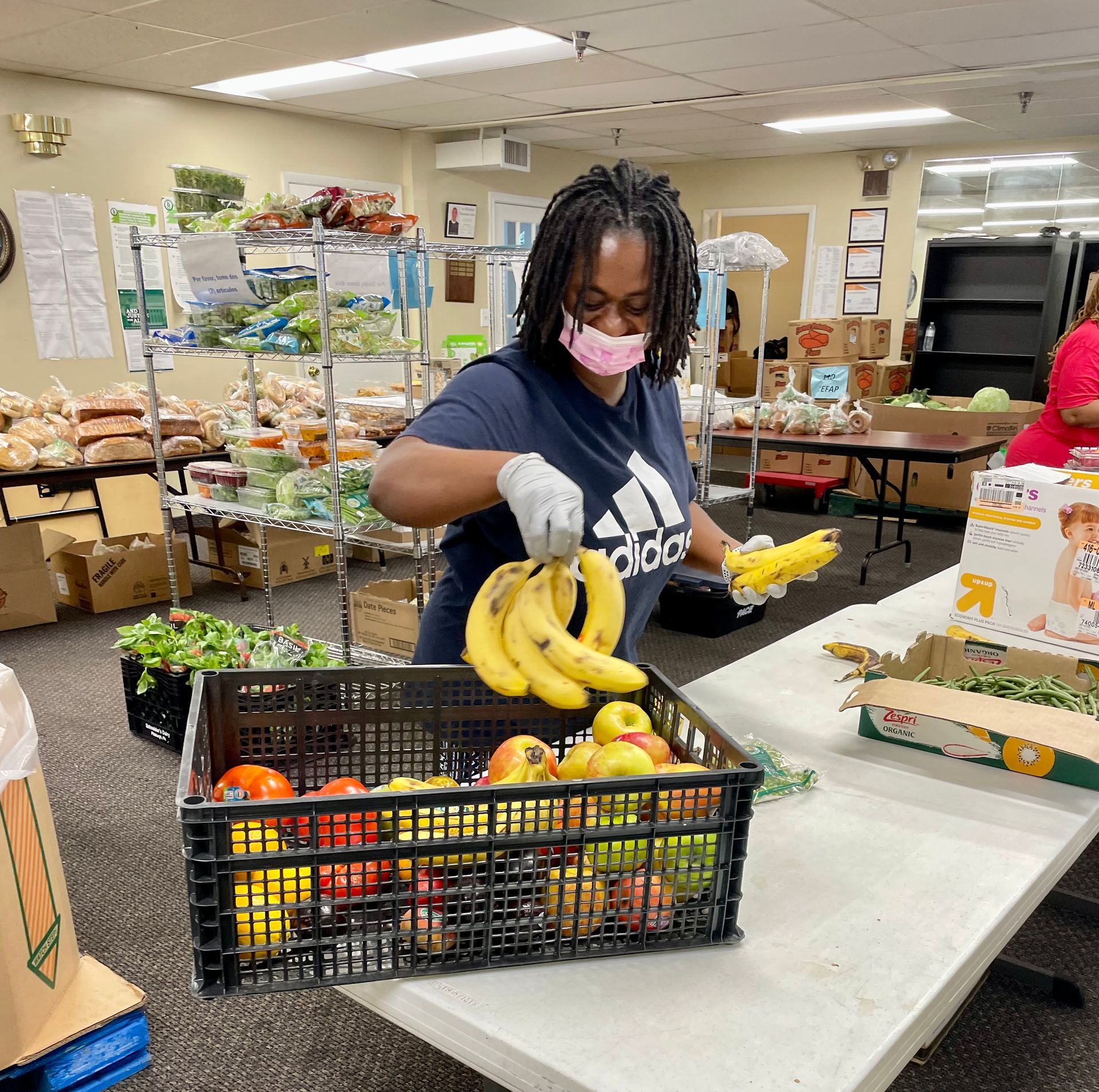 A woman wearing a mask is putting bananas in a basket