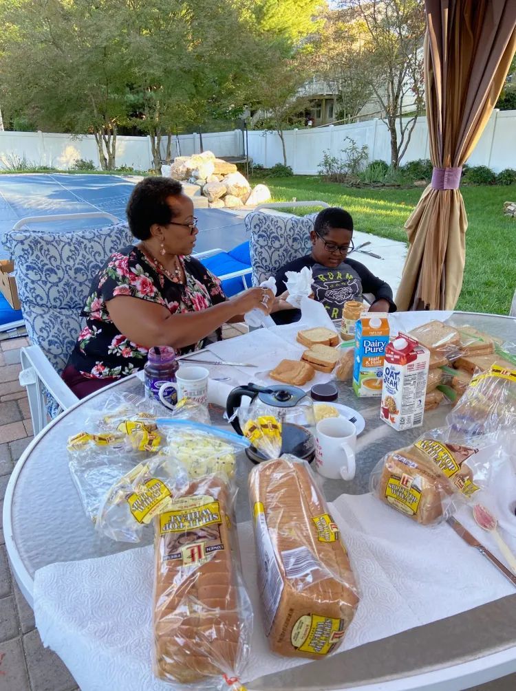 A woman and a boy are sitting at a table with bread and milk.