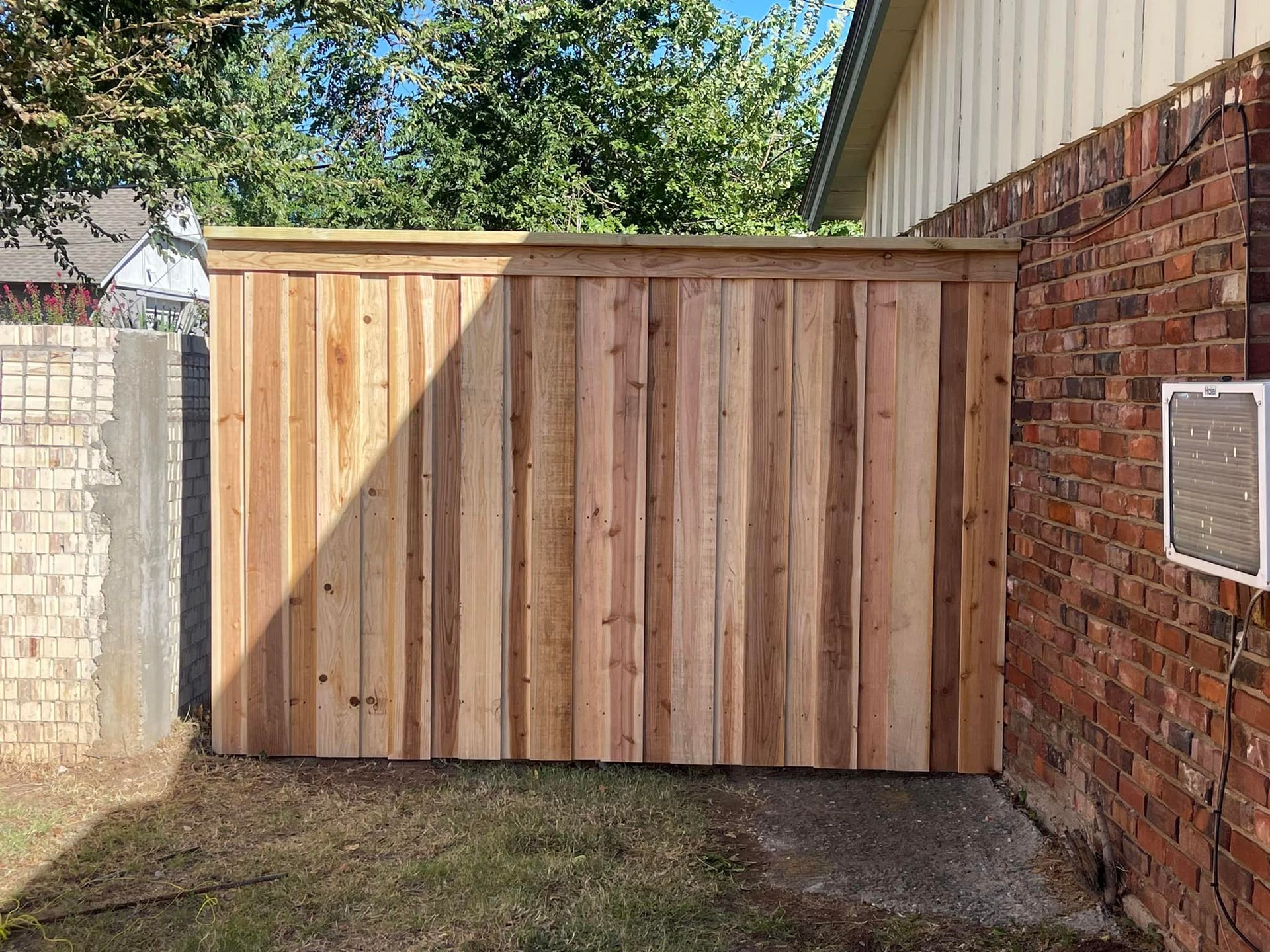 A wooden fence is sitting next to a brick wall.