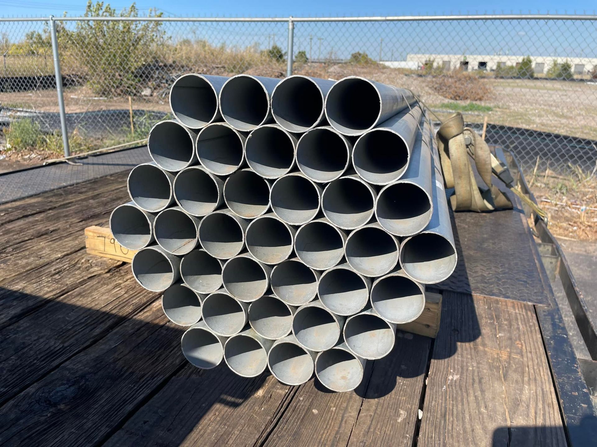 A bunch of metal pipes are stacked on top of each other on a wooden table.