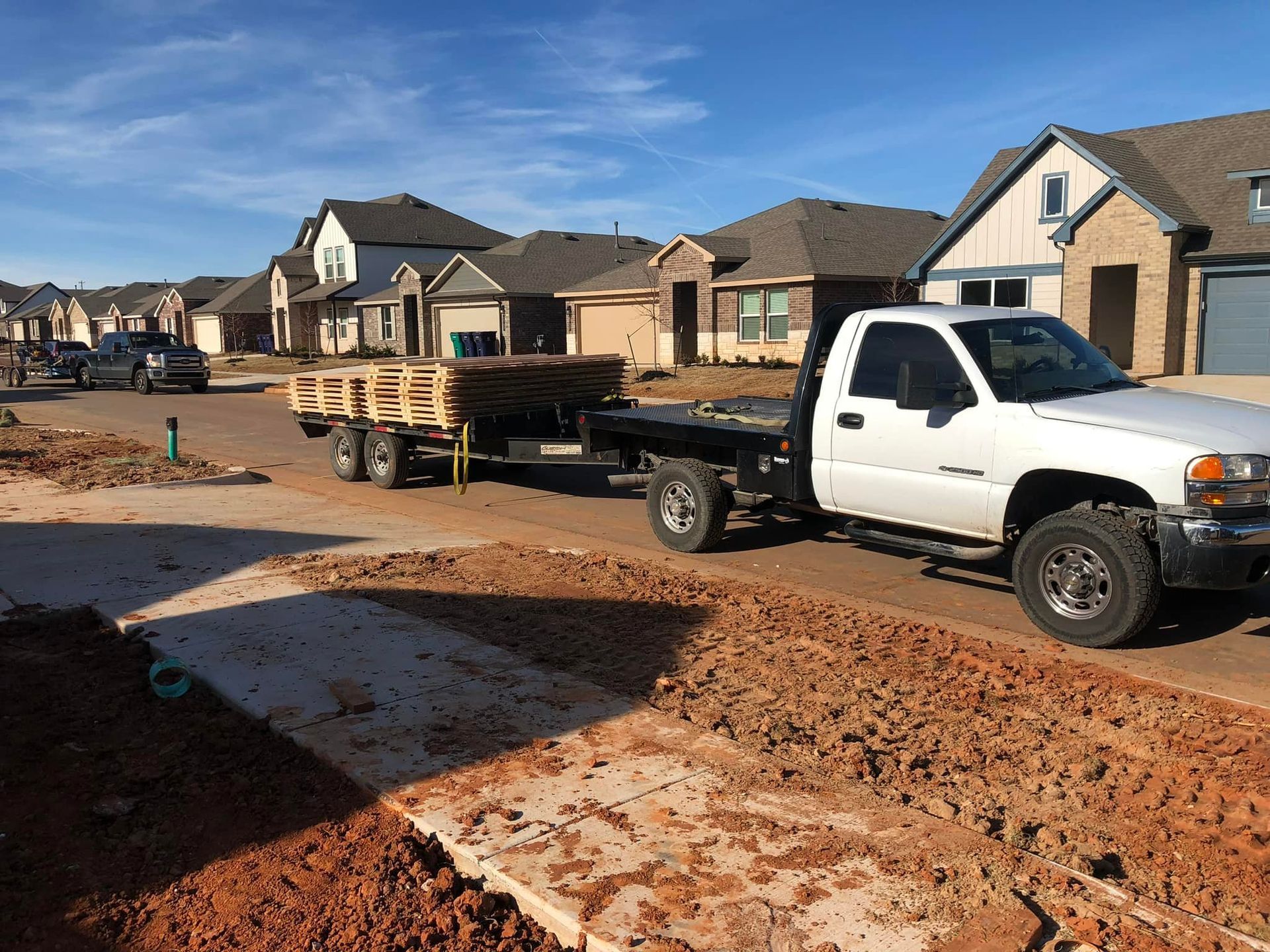 A white truck with a trailer is parked on the side of the road.