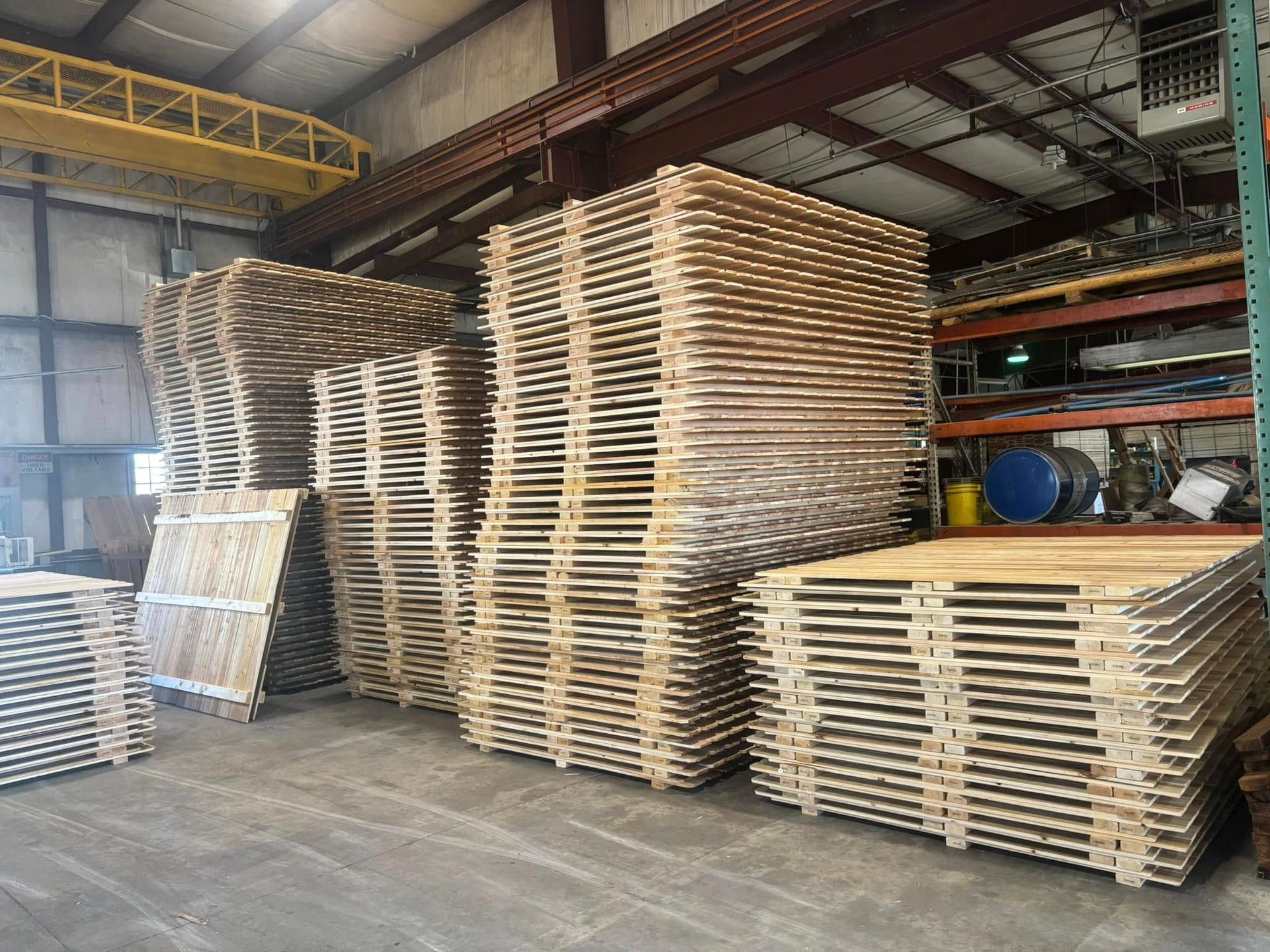 A warehouse filled with lots of wooden pallets stacked on top of each other.