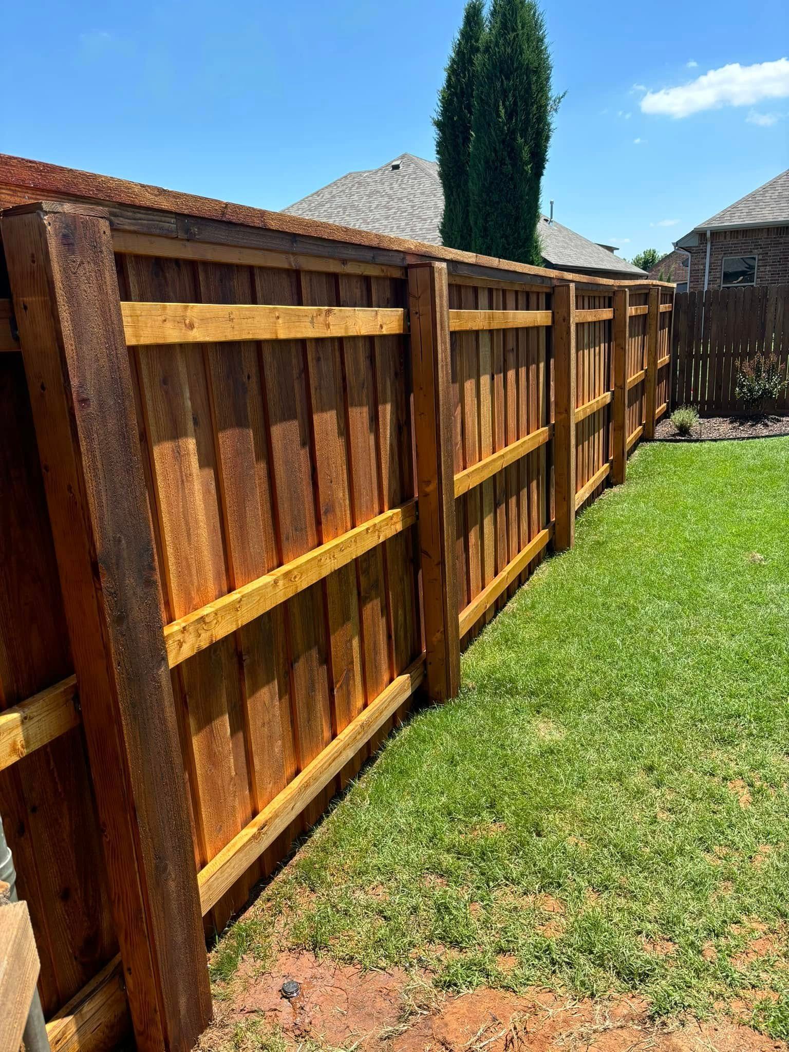 A wooden fence is sitting in the middle of a lush green yard.