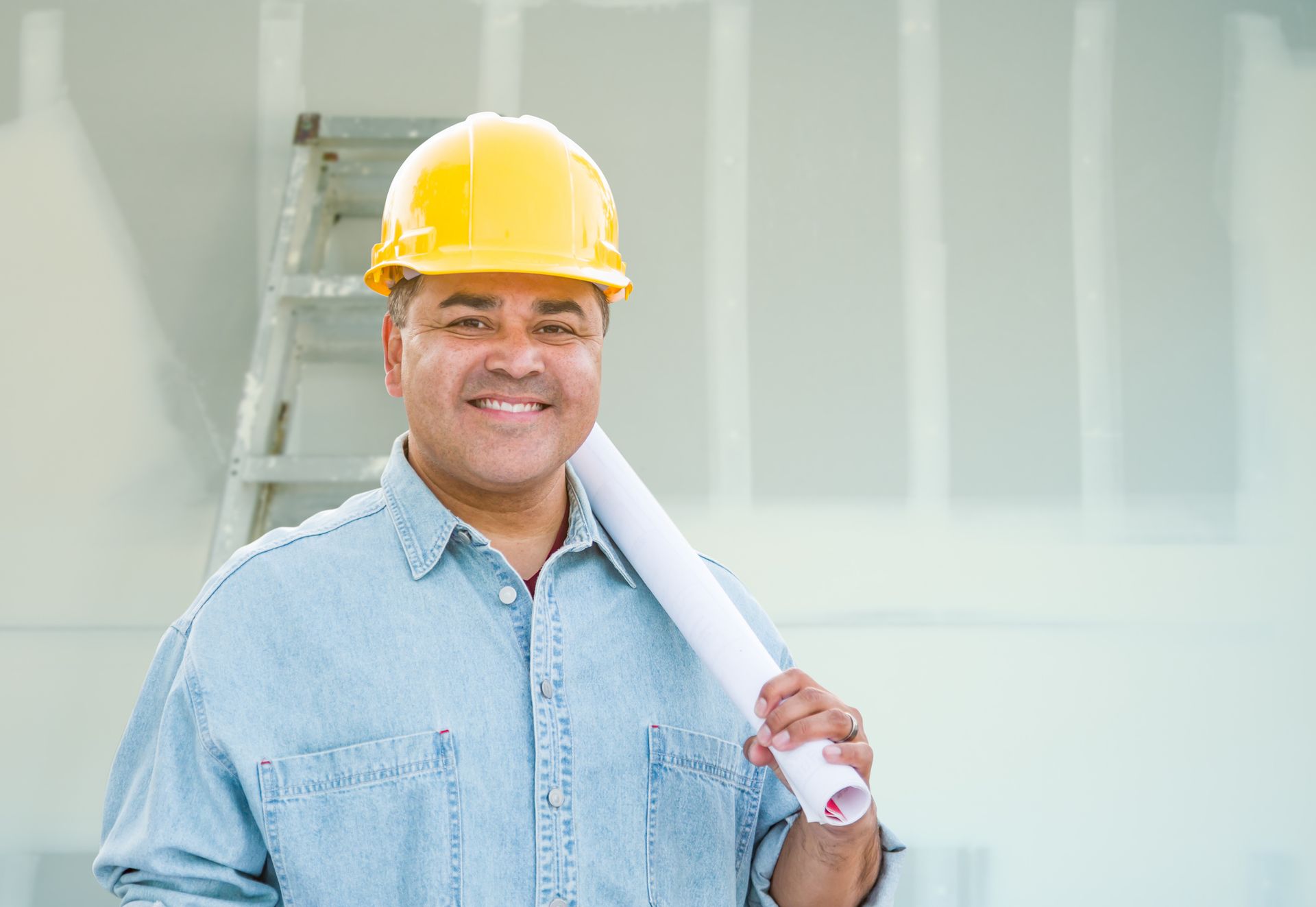 Person wearing a hard hat and holding a blueprint. Person wearing a hard hat and holding a blueprint.