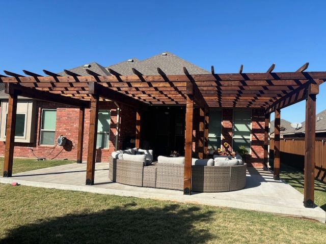 A wooden pergola with a round couch underneath it