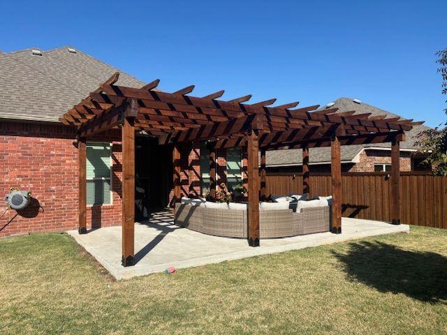 A wooden pergola is in the backyard of a house.