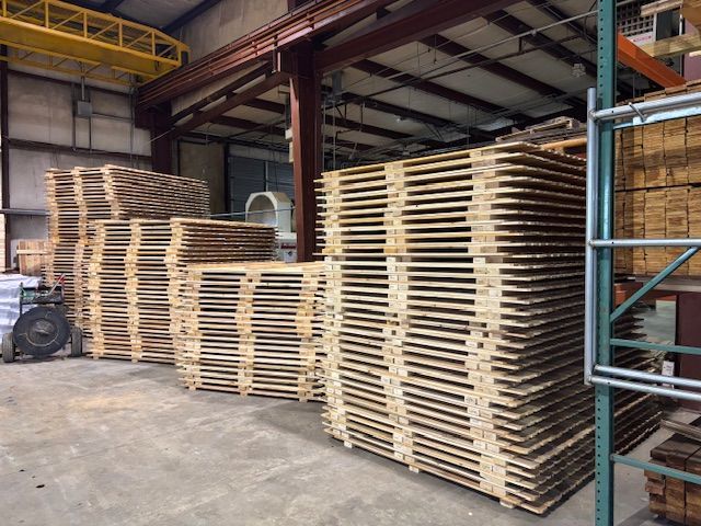 A warehouse filled with lots of wooden pallets stacked on top of each other.
