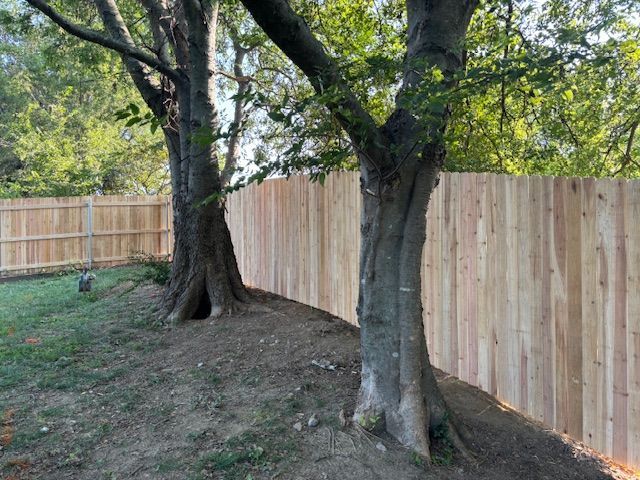 White vinyl privacy fence installed by a professional fence contractor in a green yard. 