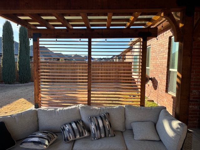 A patio with a couch and pillows under a pergola
