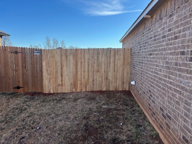 A wooden fence is sitting next to a brick wall.