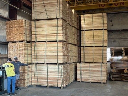 Stacks of bundled lumber piled high inside a warehouse.