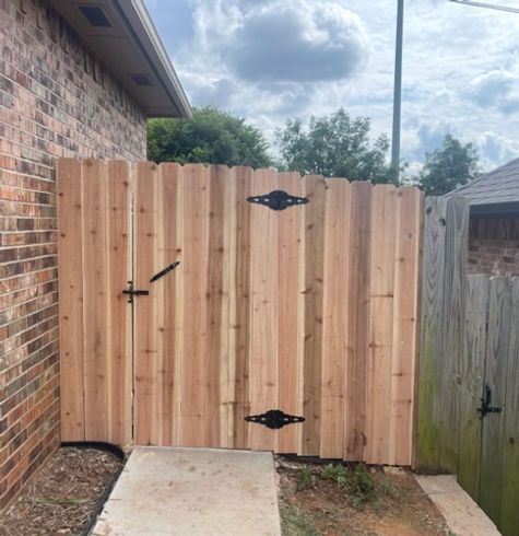 A wooden fence is next to a brick house.