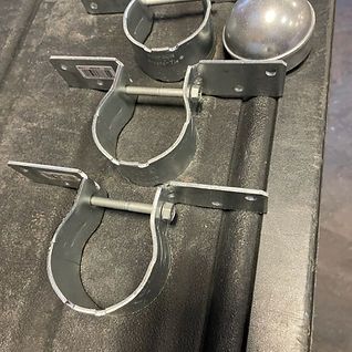 A bunch of metal pipe clamps are sitting on top of a table.