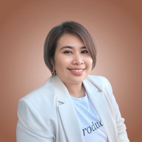 Smiling person in a white blazer and shirt against a soft pink background