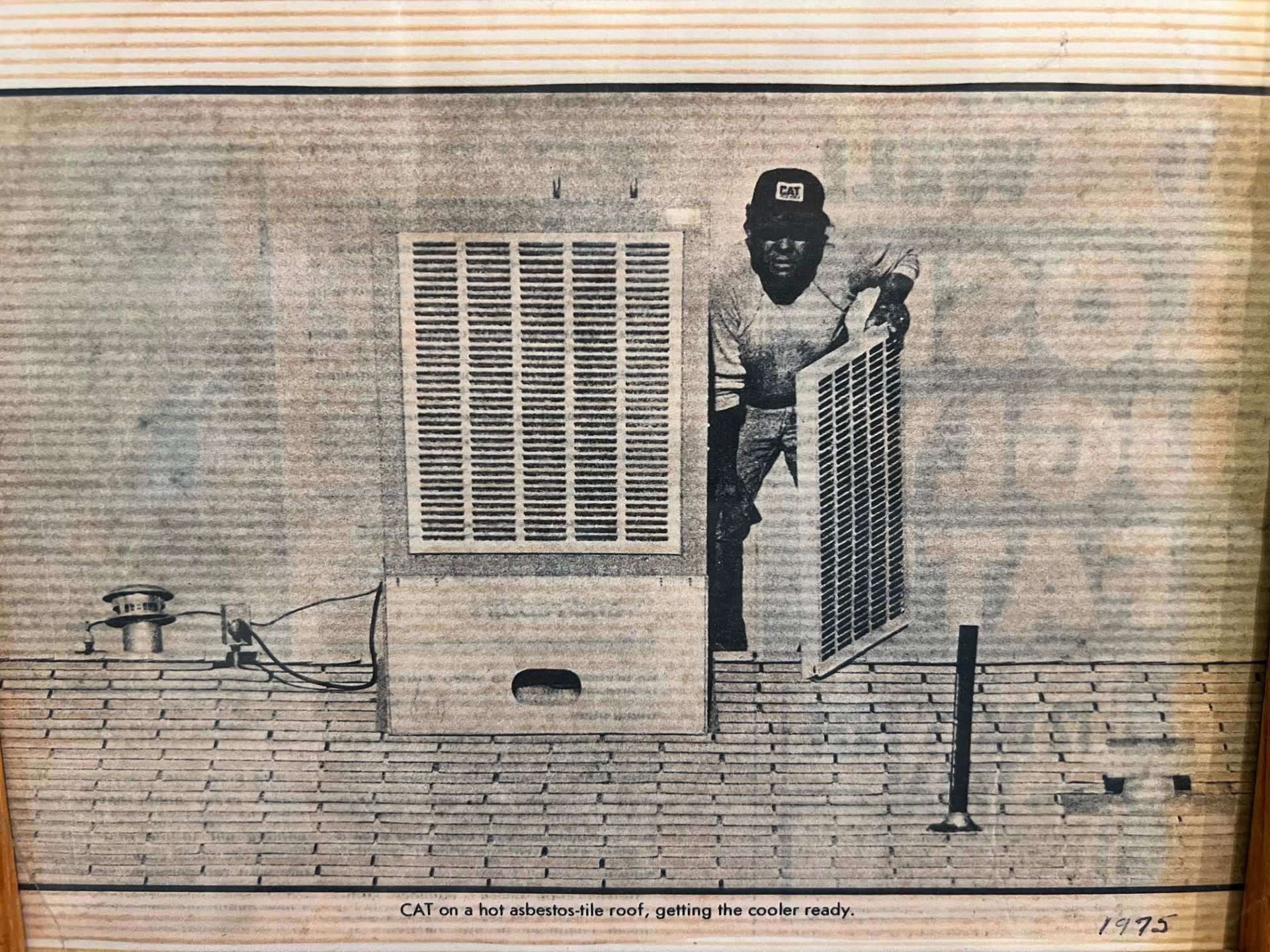 An African American man on a brick roof removes an air cooler filter. He wears a cap and is preparing the cooler.
