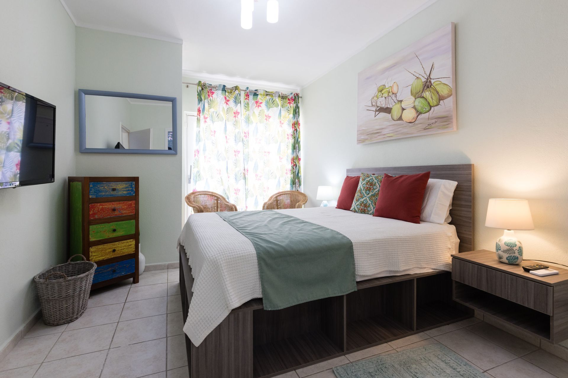 A bedroom with a king size bed , dresser , lamp and television.