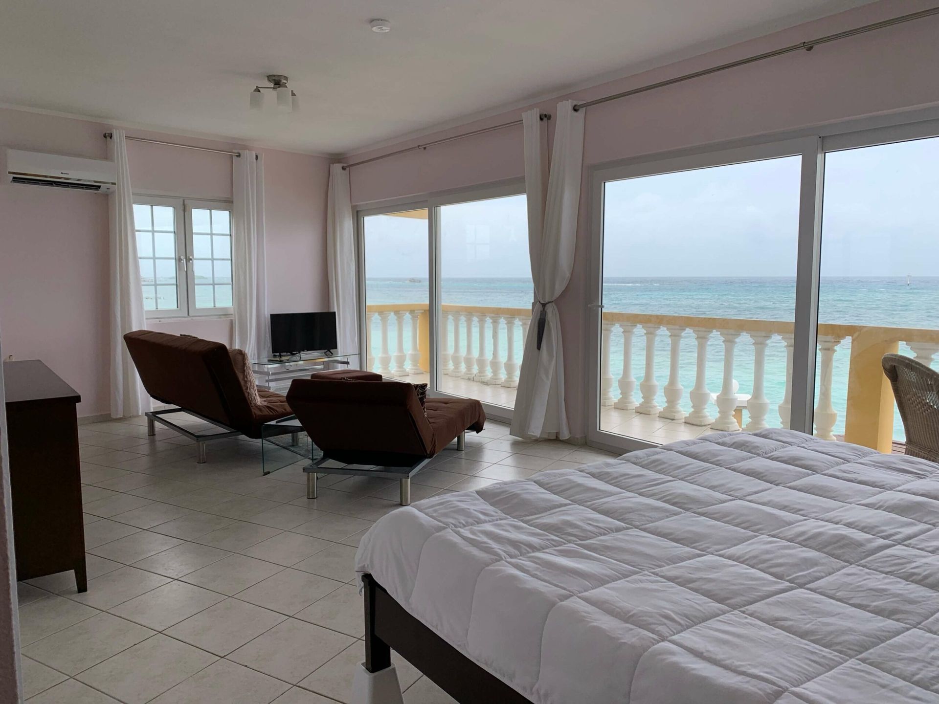 A bedroom with a large bed and a balcony overlooking the ocean.