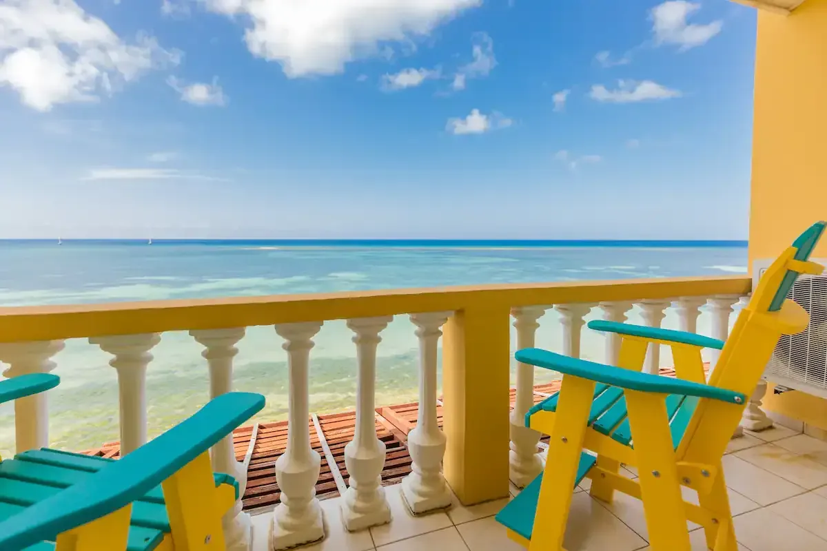 A balcony with two chairs and a view of the ocean