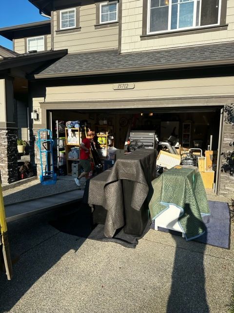 Moving: A garage filled with boxes, a man, and wrapped furniture.